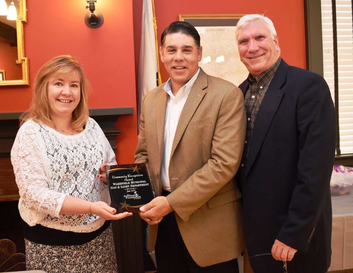 A man and two women holding a plaque.