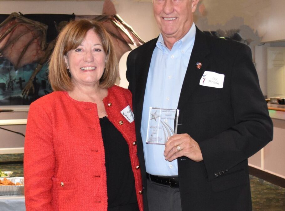 Two people posing with an award between them.