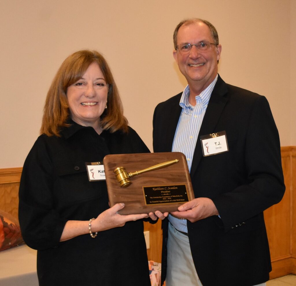 A man and woman holding a plaque with a hammer.